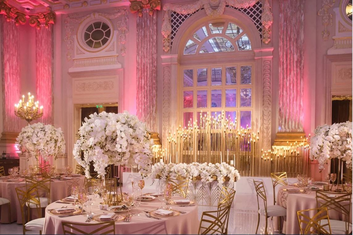 Ballroom reception with pink uplighting, tall candelabra and white floral centrepieces