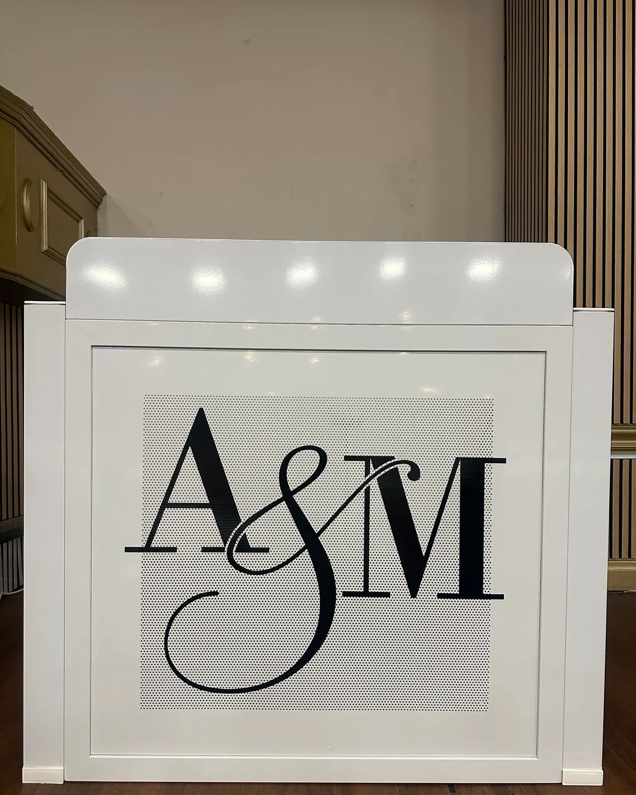 White DJ booth front printed with the couple’s A&M monogram